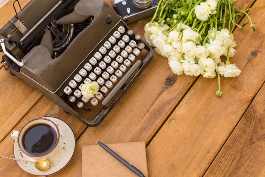 Vintage typewriter, cup of coffee, pen, flowers