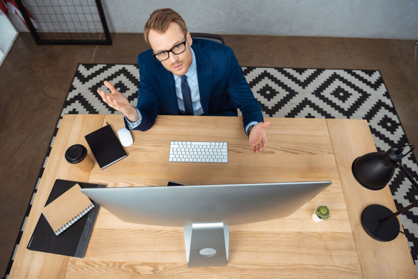 Guy at desk with computer, gesturing with hands